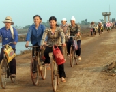 Women bike on the way home after collecting aquatic resources in Xuan Thuy National Park
