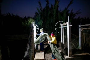 Surakit Laeaddee and his worker hold up a shrimp net at his shrimp farm in Leam Fa Pha, Thailand