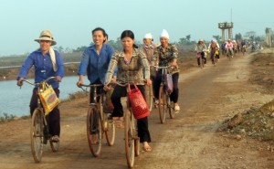 Women bike on the way home after collecting aquatic resources in Xuan Thuy National Park