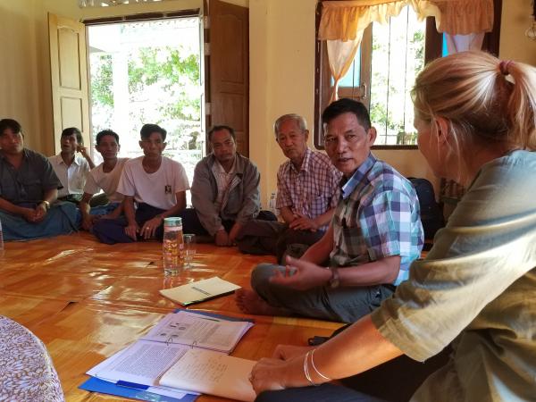 A group of community members sit on the floor during a discussion