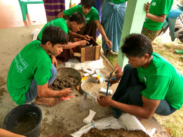 Four men in matching green shirts practice the different steps to making stoves