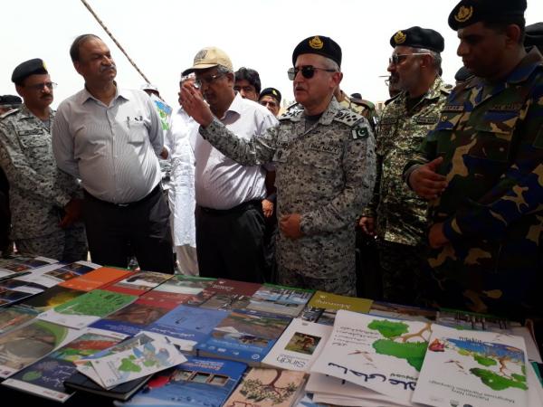 Several men in navy fatigues and civilian clothes, a table covered in brochures